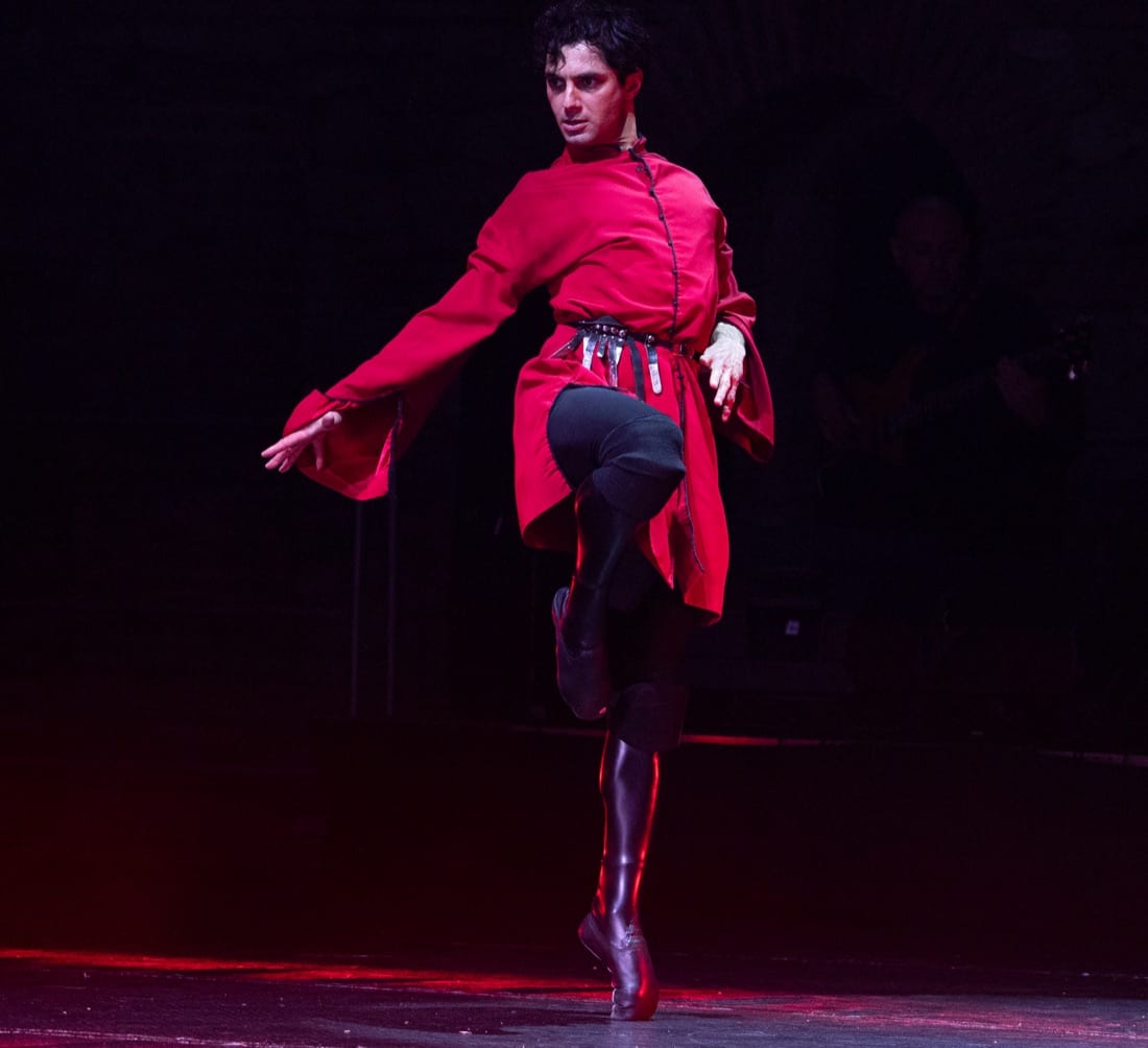Male dancer in a red chokha balancing on his toes